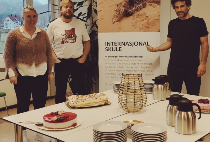 Dame og to menn med kakefeiring for internasjonal skule